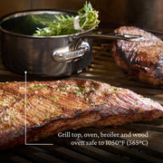 Hestan | Cookware .75qt Butter Warmer Pan on grill, showcasing its durability and heat resistance, with herbs in background saucepan. Ideal for precise cooking and melting tasks.