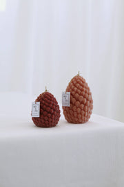 Mo&Co Home Exclusive: Sculpted Beeswax Pine Cones, detailed pine-cone–shaped candles with textured scales, hand-poured, evoking refined holiday style, designed for elegance and warmth.