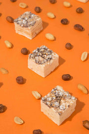 Malvi Mallow - Fluffy Nutter 4-Pack features creamy marshmallows with nuts and chocolate, arranged on an orange background, highlighting their nutty and airy composition.