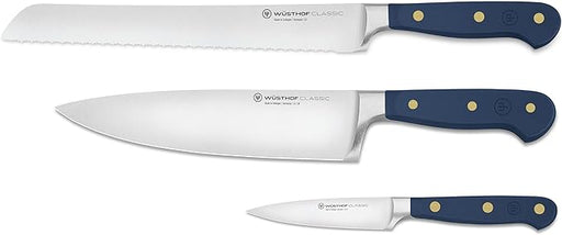 Wüsthof | Classic Wild Blueberry 3-Piece Starter Knife Set featuring a serrated bread knife, chef’s knife, and paring knife with dark-blue handles and brass rivets.