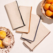 ATELIER SAUCIER - Dune Napkins | Set of 4 displayed with fruit bowls, featuring natural-beige linen with bold trim colors, embodying elegance for Athens Cooks' curated kitchen collection.