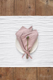 Set of 2 MagicLinen napkins on a wooden table, featuring a tied flower arrangement. Perfect for enhancing table decor with sustainable, stylish linen.