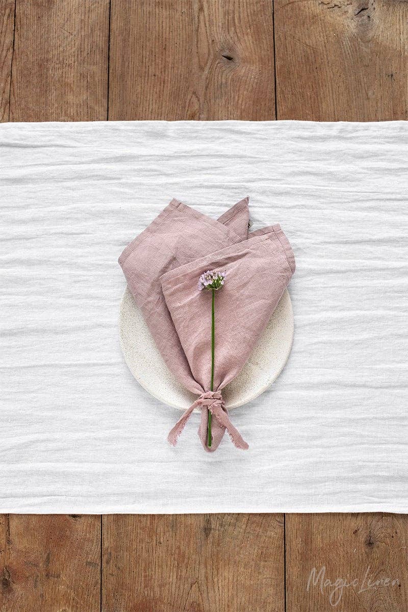 Set of 2 MagicLinen napkins on a wooden table, featuring a tied flower arrangement. Perfect for enhancing table decor with sustainable, stylish linen.