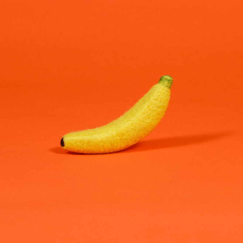 Ware of the Dog - Boiled Wool Banana Dog Toy, needle-felted from 100% wool, handmade by craftswomen in Nepal, sized at 7.5 inches, set against an orange backdrop.