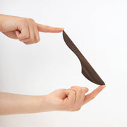 Collin Garrity - Wooden Spreader: Walnut, held in hands, showcasing its thin, curved design for spreading cheese, butter, or jam on rustic bread.