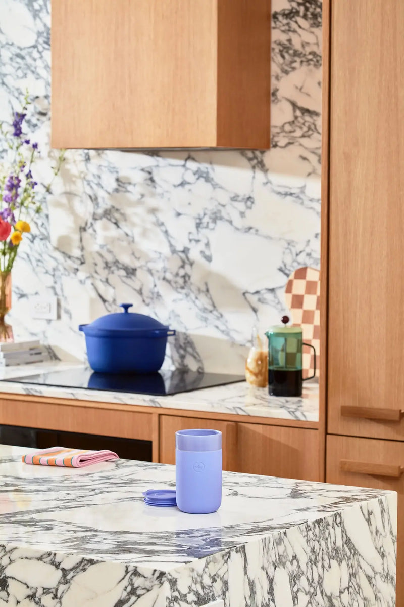 W&P - Reusable Ceramic Mug: Terrazzo Charcoal / 16 oz on a marble counter with a splash-resistant lid and silicone sleeve.