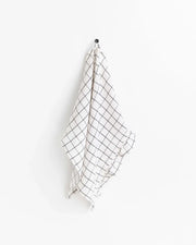 MagicLinen - Ruffle trim tea towel with black lines, hanging on a hook, showcasing its soft, absorbent linen texture.