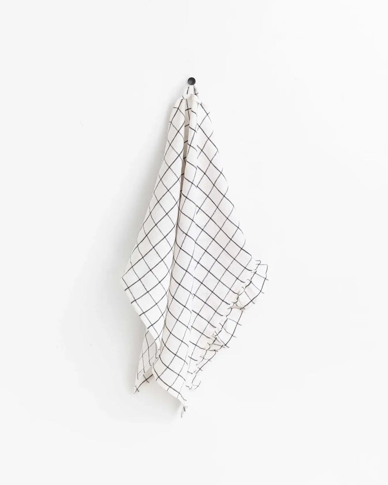 MagicLinen - Ruffle trim tea towel with black lines, hanging on a hook, showcasing its soft, absorbent linen texture.