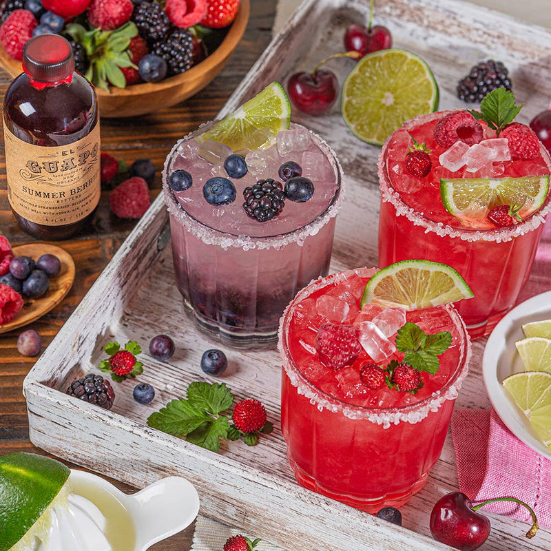 El Guapo - Bitters: Summer Berries showcased with fresh fruit and drinks, emphasizing their use in cocktails, made from Louisiana strawberries and berries.