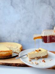 Runamok - Salted Caramel Infused Maple Syrup 250ml drizzled over a cheesecake slice with a nut crust, showcasing its versatility for desserts or breakfast.