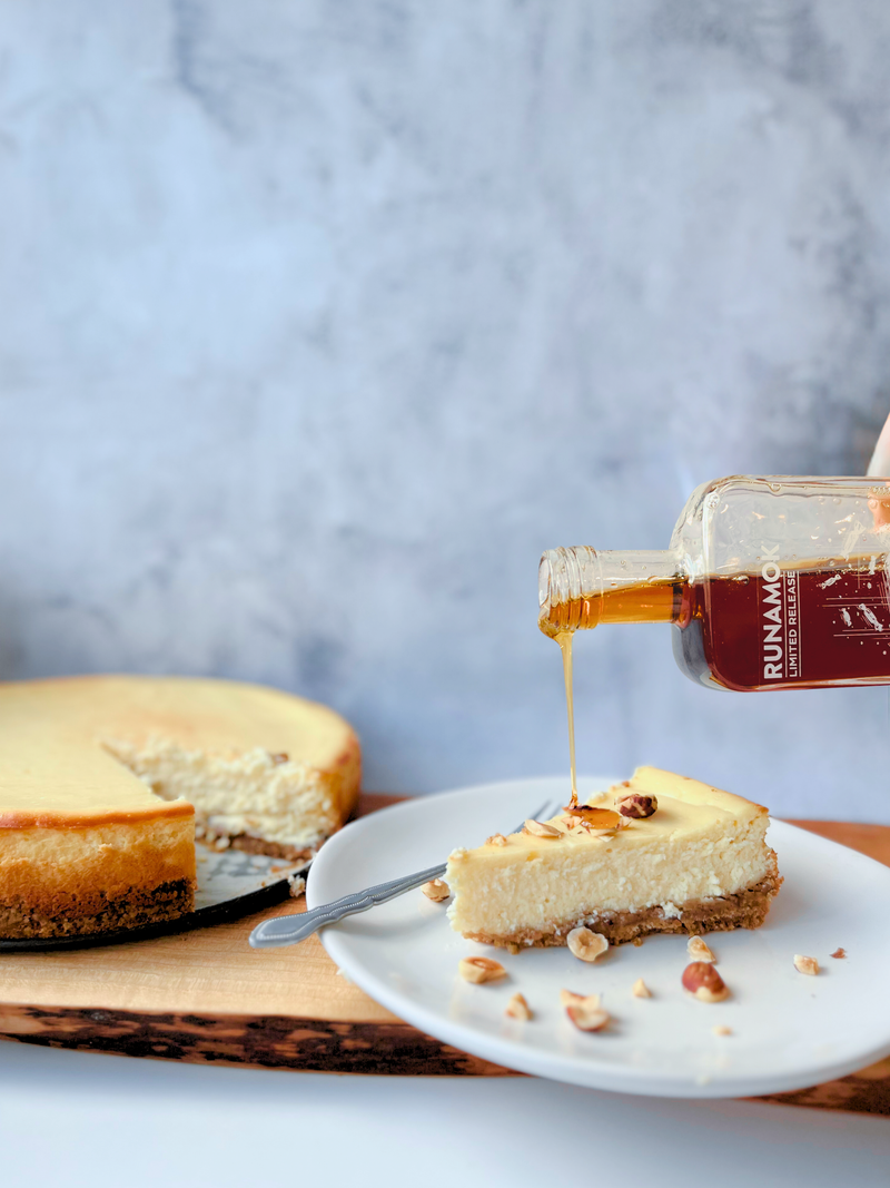 Runamok - Salted Caramel Infused Maple Syrup 250ml drizzled over a cheesecake slice with a nut crust, showcasing its versatility for desserts or breakfast.
