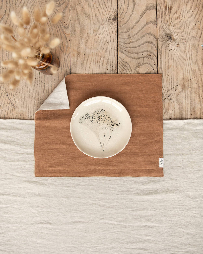 MagicLinen - Double Layer Linen Placemat Set of 2: Charcoal grey placemats displayed under a floral plate on a wooden table setting.