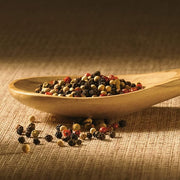 Bérard Olivewood Spoon, 13 inches, rests amid peppercorns and beans, showcasing its elegant grain pattern, exemplifying Athens Cooks' dedication to quality kitchenware.