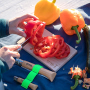 The Opinel | Nomad Cooking Kit showcases a wooden-handled knife slicing a red pepper, with additional knives and vegetables on a branded cutting board.