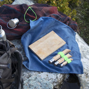 Opinel | Nomad Cooking Kit staged on a rock, featuring folding knives, a cutting board, and accessories, perfect for outdoor meal prep.