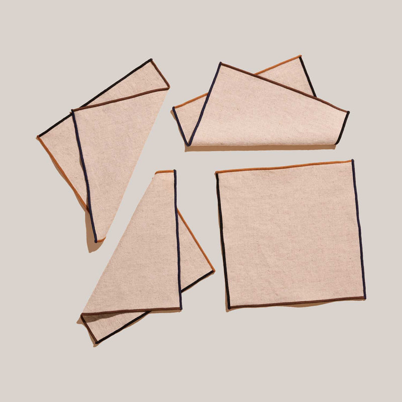 ATELIER SAUCIER - Dune Appetizer Napkins | Set of 4: Beige linen napkins with contrasting trim, arranged on a neutral background, showcasing elegant, versatile tableware.