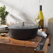 Staub | Wide Oval Dutch Oven - Graphite Grey, a large cast iron pot with a self-basting lid, ideal for braising and roasting, shown in a kitchen setting.