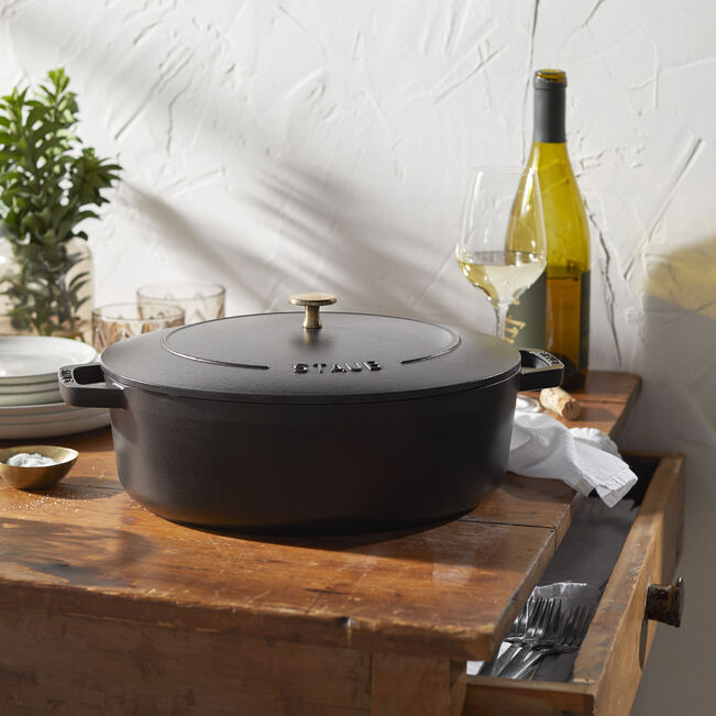 Staub | Wide Oval Dutch Oven - Graphite Grey, a large cast iron pot with a self-basting lid, ideal for braising and roasting, shown in a kitchen setting.