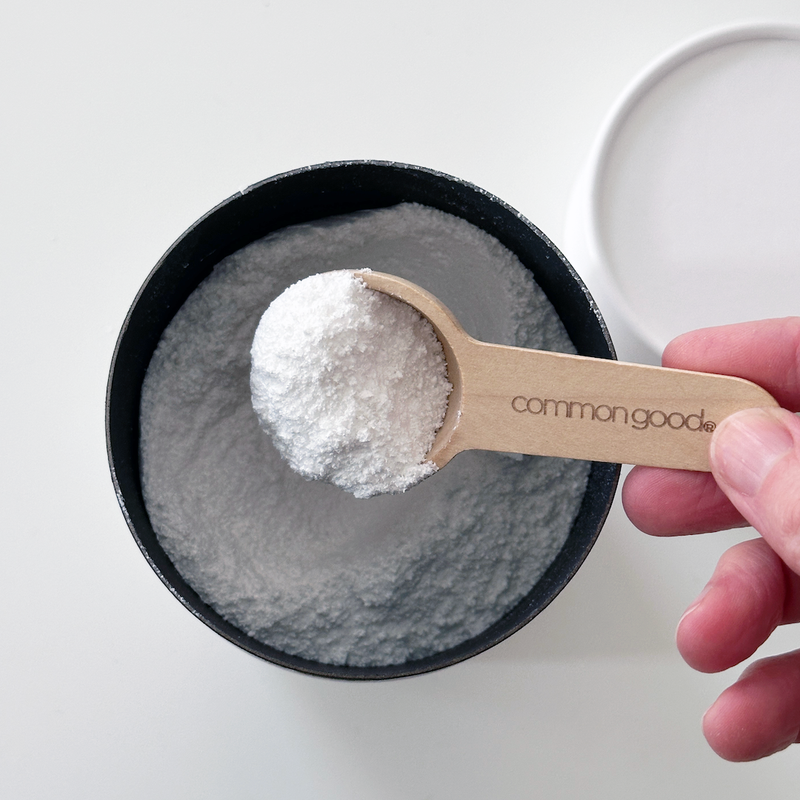 Common Good - Dishwasher Powder spooned into a bowl, highlighting its powder form and effectiveness for grease-free, sparkling dishes. Available at Athens Cooks.