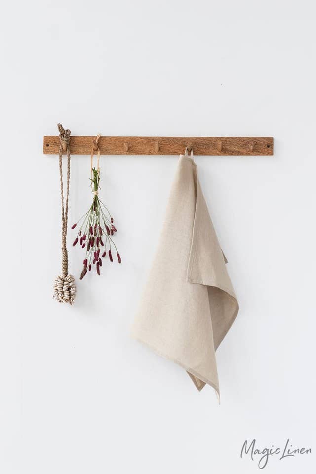 Linen tea towel hanging on a hook, showcasing its high-quality European linen fabric with a loop for easy storage, ideal for kitchen use.