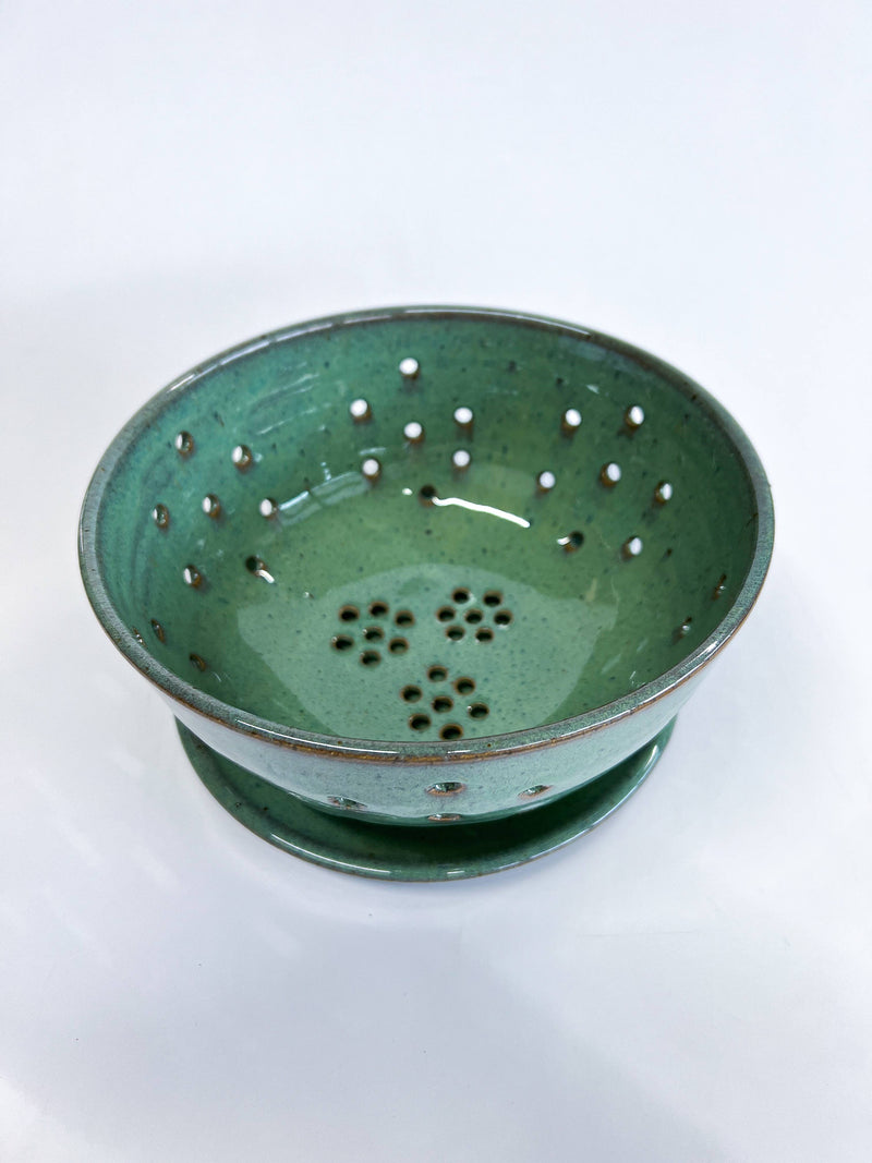 RachaelPots - Large Berry Bowl With Dish: Black. Green-glazed ceramic colander with floral drainage holes, on a matching saucer, perfect for rinsing or displaying fresh produce.