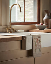 Coral & Tusk - Mushroom Tea Towel draped over a farmhouse sink with a toadstool design, enhancing a cozy kitchen vignette at Athens Cooks.