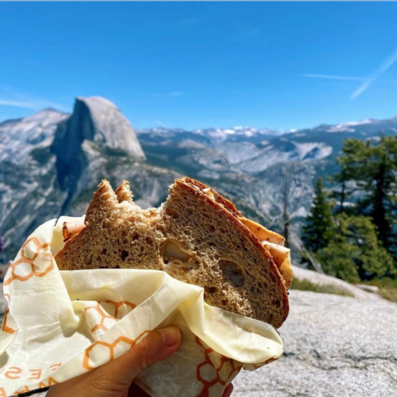Bee's Wrap - Assorted 5 Pack - Honeycomb held near mountains, illustrating its outdoor utility for preserving food during picnics or hikes.