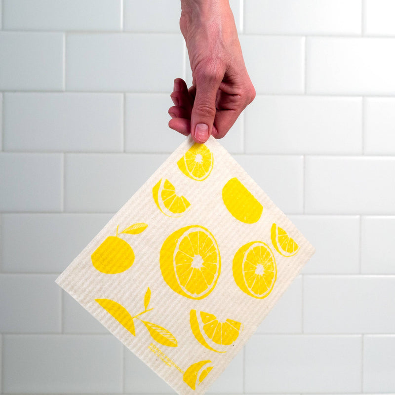 Bespoke Provisions - Lemons Swedish Dishcloth held in hand, showcasing lemon design. Made from cotton and cellulose, it's hygienic, washable, and eco-friendly.