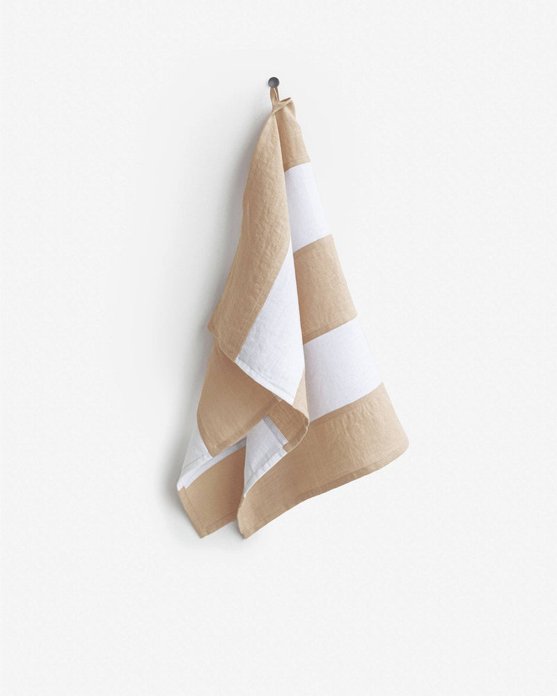 Striped linen tea towel on hook, showcasing its hanging loop. Part of MagicLinen's zero-waste collection, ideal for stylish, eco-friendly kitchen use.