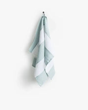 Striped linen tea towel hanging on a hook, showcasing its soft, absorbent texture and loop for easy hanging. Part of a zero-waste program.