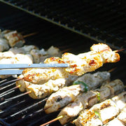 Küchenprofi | Tweezer Tongs, 8.75 in use, expertly handling chicken skewers on a barbecue grill, showcasing their precision and versatility in cooking tasks.
