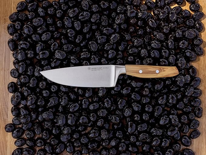 Wüsthof Amici 6 Chef's Knife resting on black olives, showcasing its precision and quality as a premium kitchen tool from Athens Cooks.