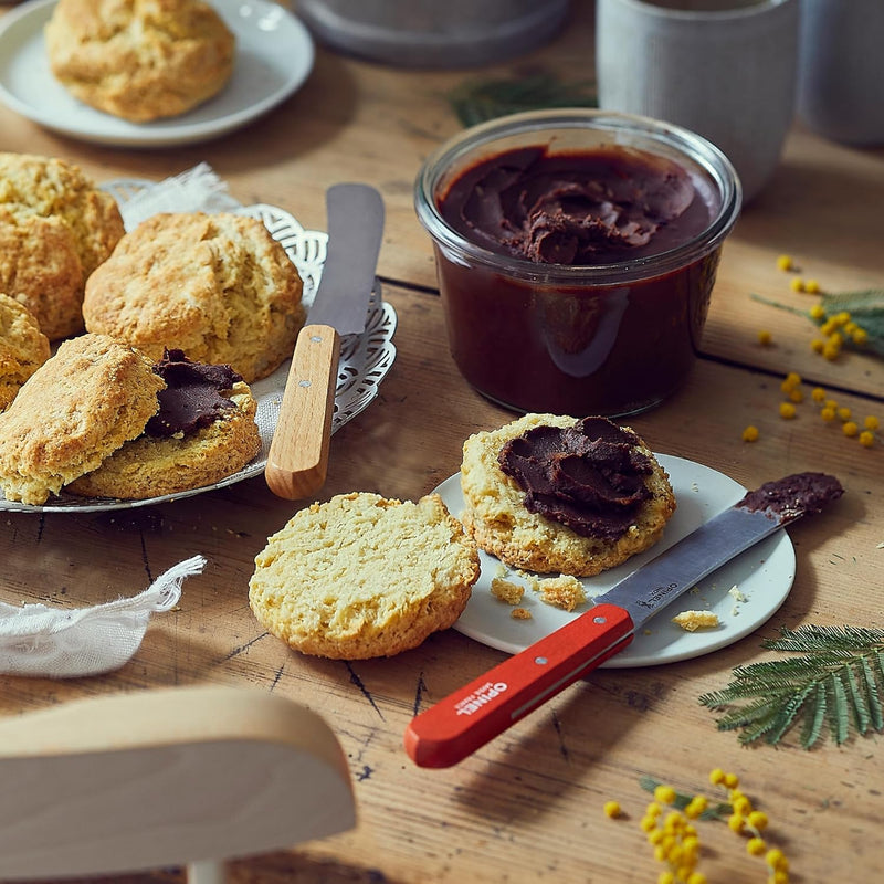 Opinel | Brunch Knives, Natural, displayed with scones and chocolate spread, featuring a red-handled knife ideal for spreading and cutting.