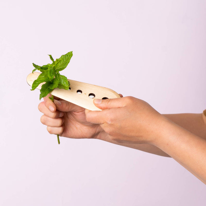 Collin Garrity - Herb Stripper: Walnut in hands, showing mint leaves being efficiently stripped from a stem through drilled holes, highlighting its practical use.