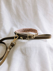 EMBER & IVORY - Olive/Blush Macrame & Leather Dog Collar: S, showcasing a brown leather collar with pink macrame, small bell, and brass fittings, on white fabric.