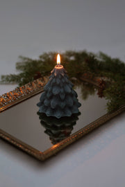 Mo&Co Home Exclusive: Sculpted Beeswax Tree candle on mirror, reflecting its intricate evergreen design, surrounded by real boughs; embodies holiday nostalgia and elegance.