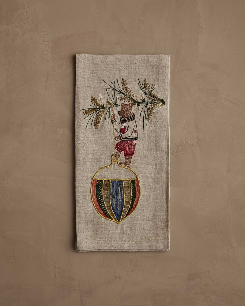 Coral & Tusk - Deck the Halls Bear Tea Towel features a brown bear in festive attire, embroidered on natural linen, perfect for holiday kitchen decor.
