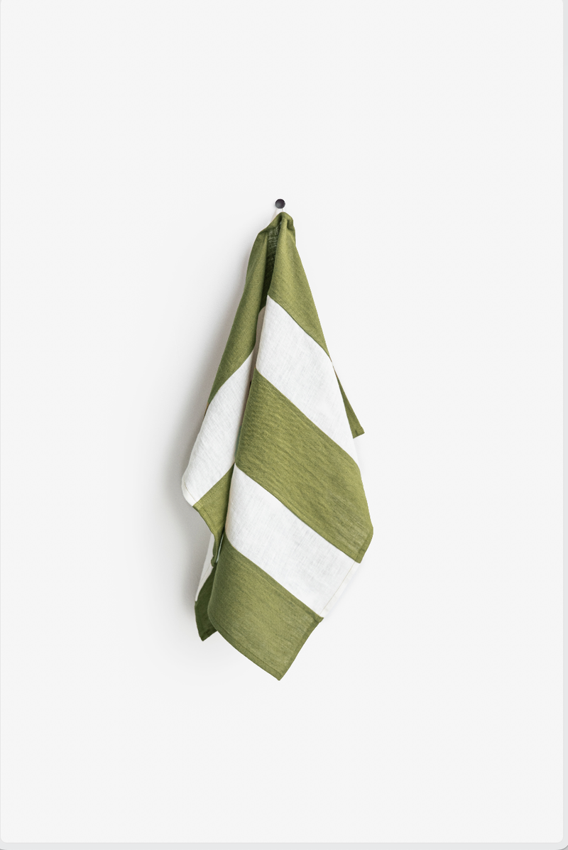 Striped linen tea towel with a hanging loop, part of MagicLinen's zero-waste collection, displayed on a hook, emphasizing sustainability and practicality for kitchen use.