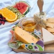 Bee's Wrap - New! Garden Party - Assorted 3 Pack displayed with fruit and cheese, highlighting its use for sustainable food storage.