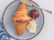 Beth's Farm Kitchen's Strawberry Rhubarb Jam pictured with a croissant, cheese slices, and a butter knife, showcasing a delectable breakfast setting.