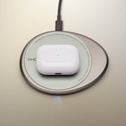 Wireless charging pad with a white earbuds case on top, part of the OHOM - Ui 3 Self-heating Mug Set, offering device charging and beverage warming.