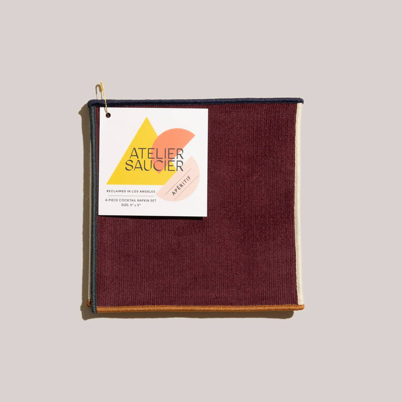 ATELIER SAUCIER - Clubhouse Cocktail Napkins | Set of 4, burgundy reclaimed fabric with contrasting edges, includes a tag noting Reclaimed in Los Angeles, folded and ready for use.
