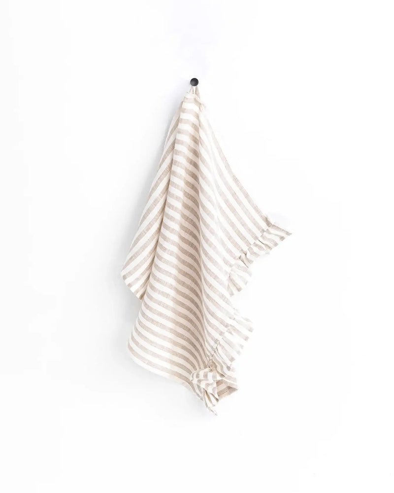 MagicLinen ruffle trim tea towel hangs on a hook, showcasing its soft, absorbent linen texture, ideal for stylish and functional kitchen use.