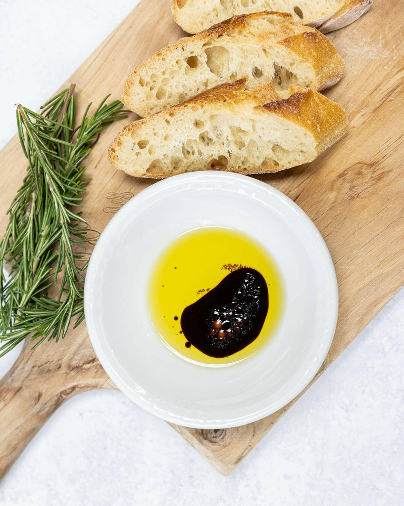 Frantoio Galantino Extra Virgin Olive Oil in Ceramic Jug, with close-up of bread, rosemary, and oil, reflecting artisanal craftsmanship and culinary excellence.