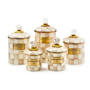 MacKenzie-Childs Mocha Check Medium Canister set features five hand-painted checkered canisters with gold accents and glass finials, ideal for chic kitchen storage.