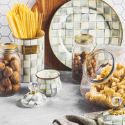 Mackenzie-Childs Sterling Check Large Canister artfully holds dried spaghetti, surrounded by glass jars of walnuts, hazelnuts, and pasta on a kitchen countertop.