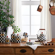 MacKenzie Childs | Cookie Jar with Courtly Check Lid sits amidst a stylish kitchen scene, displaying its checker-patterned lid beside cookies in a glass body.