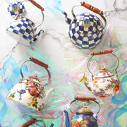 MacKenzie Childs | White Flower Market 3 Quart Tea Kettle, featuring vibrant botanical decals, wood handle, and glass knob, elegantly displayed among decorative teapots on a marble surface.