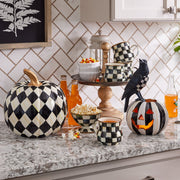 MacKenzie-Childs | Courtly Check Ice Cream Dish amidst a Halloween-themed kitchen setup, showcasing its black-and-white check pattern alongside decorative pumpkins and a two-tiered wooden stand.