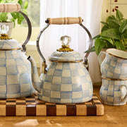 MacKenzie-Childs Sky Check Tea Kettle, 2 Qt, with wooden handle and glass-knob lid, set with matching mugs on a striped cutting board.